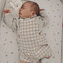 baby, sleeping, crib, plush_toy, overalls, socks, shoes, patterned_bedding, infant, peaceful, child, cute, resting, soft_toy, bed, indoor, clothing, newborn, portrait, sleep
