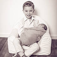 Dario a rejoint le concours — aidez-le/la à gagner de superbes lots ! child, baby, boy, newborn, smiling, sitting, armchair, clothing, floor, wooden_floor, portrait, black_and_white, monochrome, happy, indoor, people, infant, family, cute, toddler