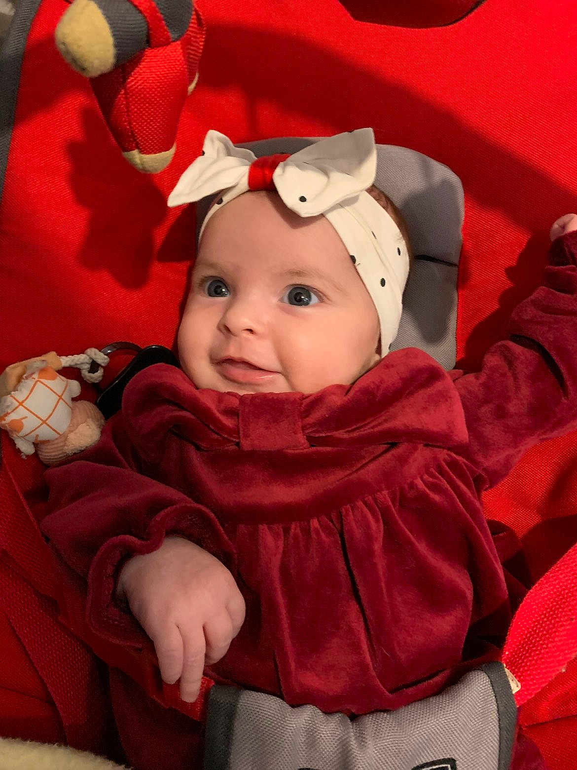 Violette participe au concours pour gagner de l'argent avec cette photo : baby, infant, headband, bow, red_clothing, velvet, cushion, seat, toy, soft_toy, smile, blue_eyes, hand, cute, indoor, child, person, portrait, happy, cozy