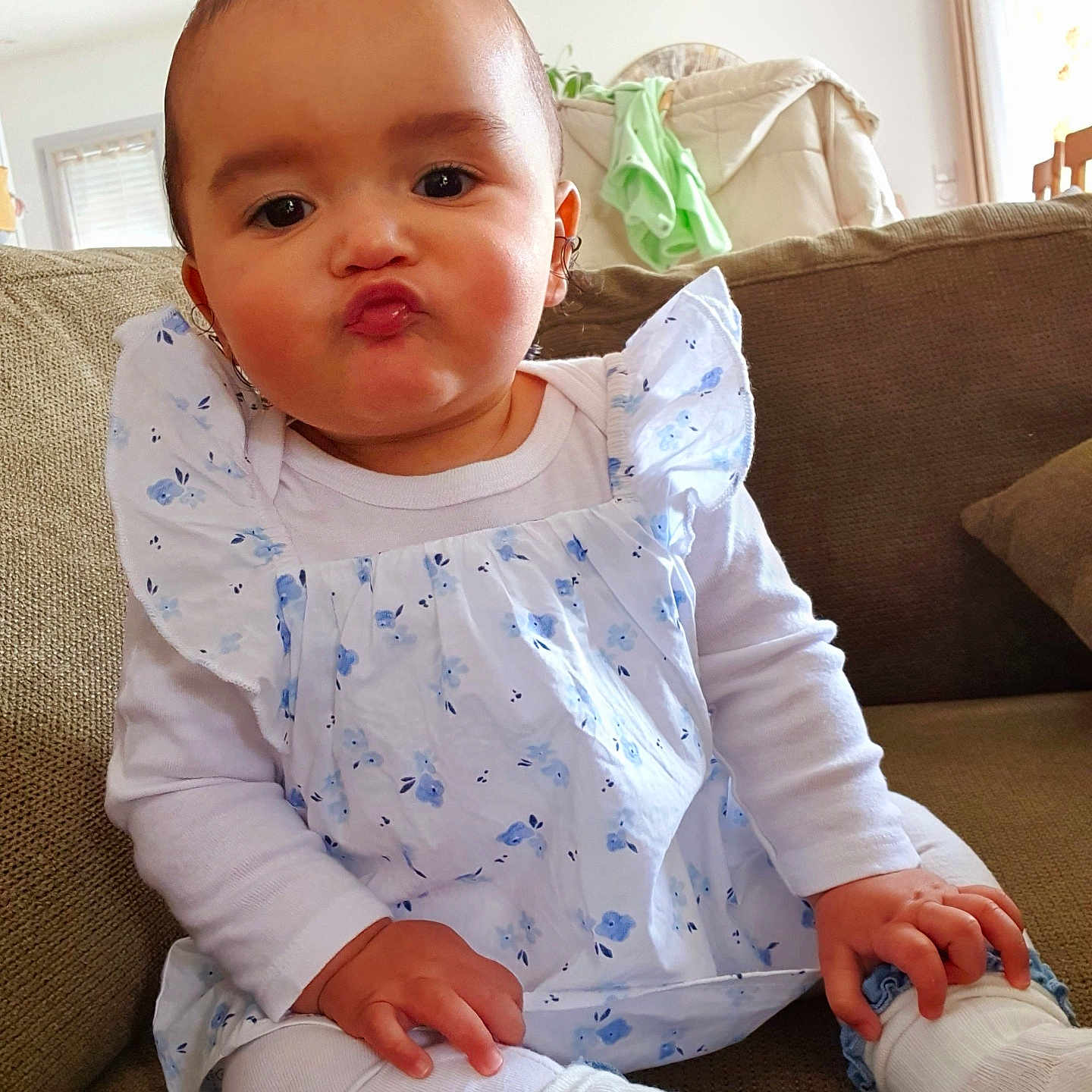 Leely-Rose participe au concours pour gagner de l'argent avec cette photo : baby, cheeks, child, couch, cute, expression, eyes, face, floral_pattern, hand, indoor, infant, living_room, mouth, nose, ponytail, sitting, skin, socks, white_clothing