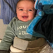 Logan a rejoint le concours — aidez-le/la à gagner de superbes lots ! baby, infant, smile, blanket, plush_toy, stuffed_animal, towel, onesie, clothing, bed, cozy, portrait, face, eyes, mouth, happy, lying_down, soft_texture, nursery, cute