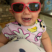 Camilla is registered to the contest to win money with this photo: toddler, child, sunglasses, smiling, indoor, kitchen, brick_wall, person, polka_dots, clothing, face, happy, young_child, furniture, background, reflection, home, curious, portrait, casual