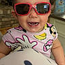 toddler, child, sunglasses, smiling, indoor, kitchen, brick_wall, person, polka_dots, clothing, face, happy, young_child, furniture, background, reflection, home, curious, portrait, casual