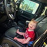 baby, child, jeep, car_interior, car_seat, black_leather, steering_wheel, smiling, happy, pigtails, red_shirt, blue_shorts, sunlight, window, seatbelt, dashboard, vehicle, infant, cute, portrait