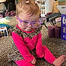 toddler, child, glasses, pigtails, pink_clothing, leopard_print, carpet, indoor, living_room, toy, basket, furniture, barefoot, sitting, cute, young_child, expression, hair_ties, home, casual