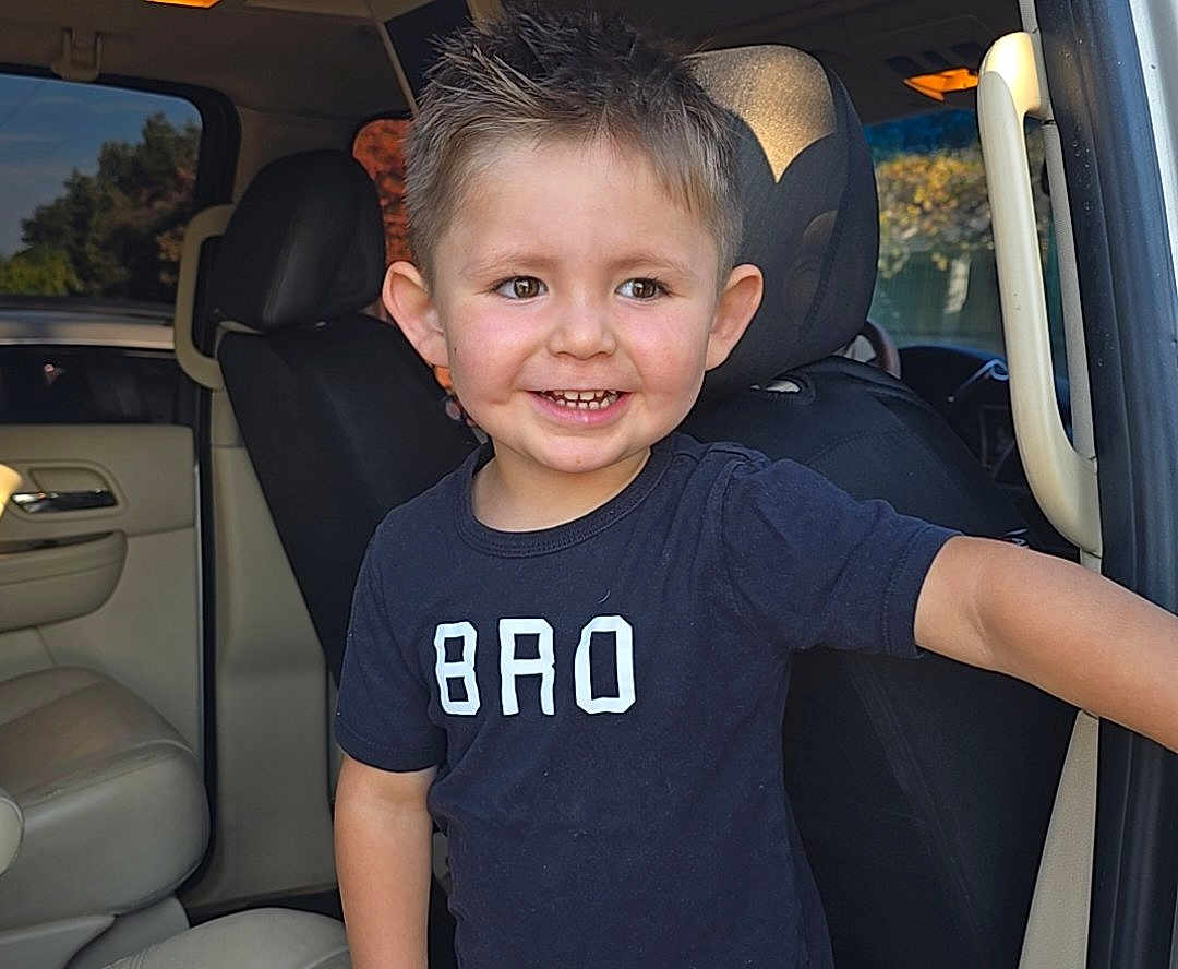 Romeo is registered to the contest to win money with this photo: child, boy, smile, tshirt, bro, car_interior, seat, window, door, happy, portrait, short_hair, young, person, daylight, casual_clothing, seatbelt, automobile, cute, indoors