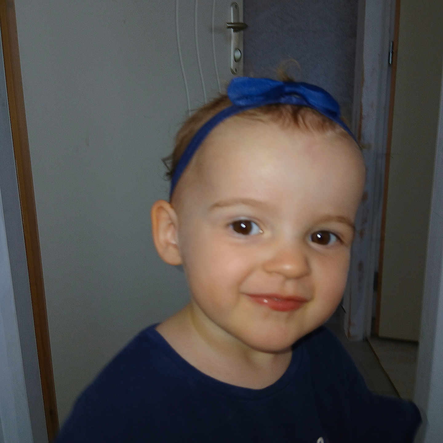 Cyndel participe au concours pour gagner de l'argent avec cette photo : baby, blue_headband, blue_shirt, child, clothing, cute, door, expression, face, happy, headband, human, indoor, person, portrait, skin, smile, standing, toddler, young_child
