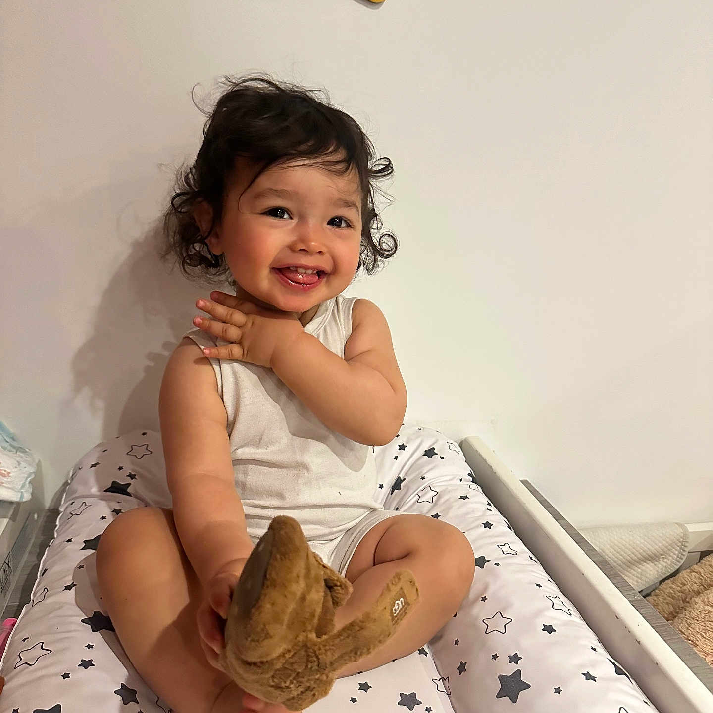 Ethan a rejoint le concours — aidez-le/la à gagner de superbes lots ! baby_clothes, barefoot, child, curly_hair, cushion, cute, ethan, happy, home, indoor, infant, nameplate, person, playful, plush_toy, sitting, smiling, star_pattern, toddler, white_wall