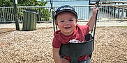 Luca is registered to the contest to win money with this photo: barefoot, cap, child, clouds, daylight, fun, greenery, happy, old_navy, outdoor, pier, playground, railing, red_shirt, sky, smiling, swing, toddler, water, wood_chips