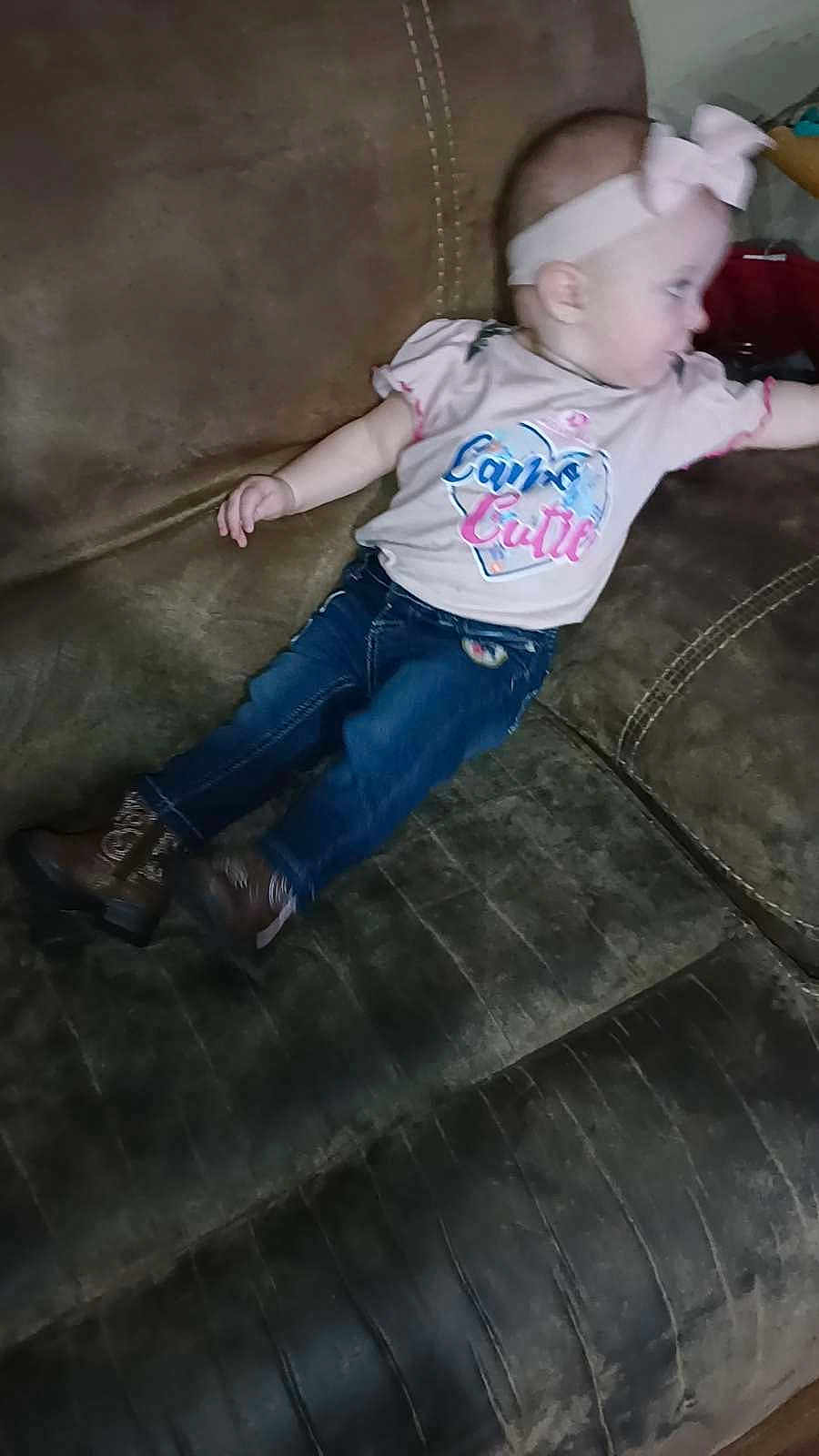 Paisley is registered to the contest to win money with this photo: baby, child, girl, jeans, shirt, headband, bow, couch, furniture, indoor, casual_clothing, footwear, boots, infant, person, relaxing, side_view, curious, home, seated