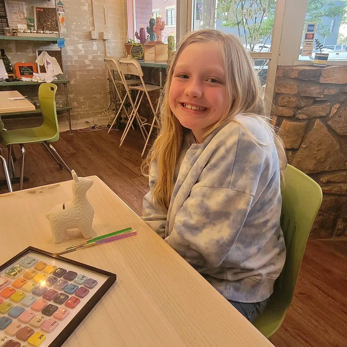 Kaylee joined the competition — help win amazing prizes! artist, chair, child, desk, floor, flooring, fun, furniture, happy, hardwood, indoor_games_and_sports, joy, leisure, person, recreation, shelf, sitting, smile, t_shirt, table