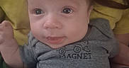 Southern is registered to the contest to win money with this photo: baby, infant, face, eyes, smile, gray_shirt, magnet_graphic, person, yellow_shirt, blanket, hand, portrait, cute, indoors, young_child, skin, hair, expression, resting, closeup