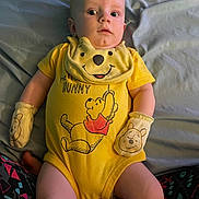 Jaxson is registered to the contest to win money with this photo: baby, infant, yellow_onesie, mittens, winnie_the_pooh, bed, blanket, patterned_pants, curious_expression, lying_down, child, person, cute, indoors, soft_lighting, clothing, portrait, small_child, sleepwear, yellow