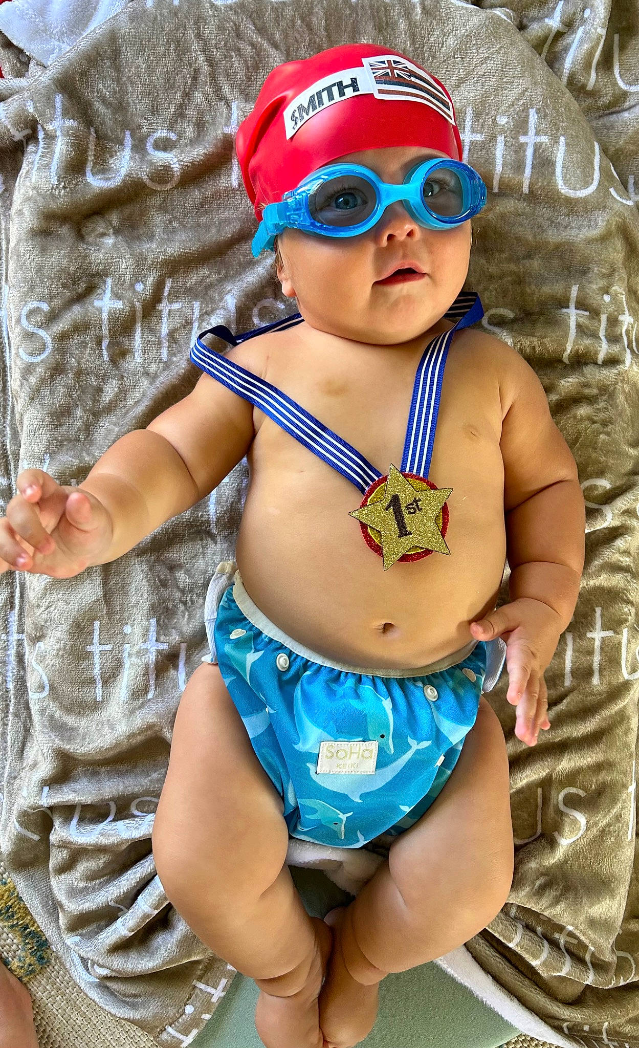 Titus is registered to the contest to win money with this photo: baby, baby_toddler_clothing, blue, cap, chest, cool, eyewear, finger, glasses, goggles, hat, headgear, headwear, human_body, person, pink, skin, sunglasses, swimwear, thigh