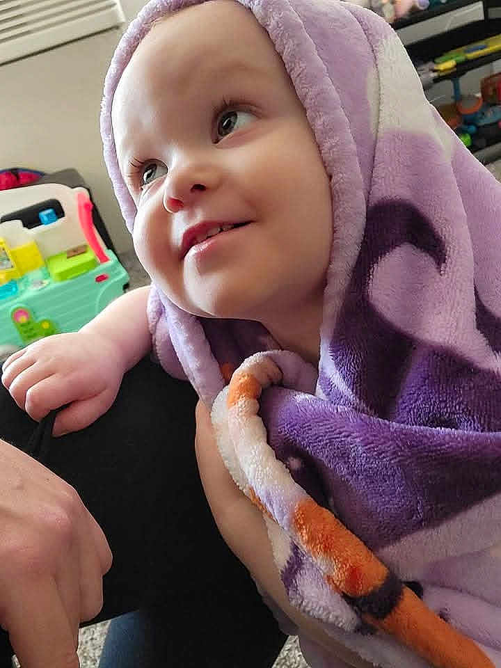 Mckensey is registered to the contest to win money with this photo: toddler, child, blanket, purple, smiling, face, indoor, toy, playroom, happy, person, cozy, closeup, infant, cute, soft, wrapped, baby, expression, young