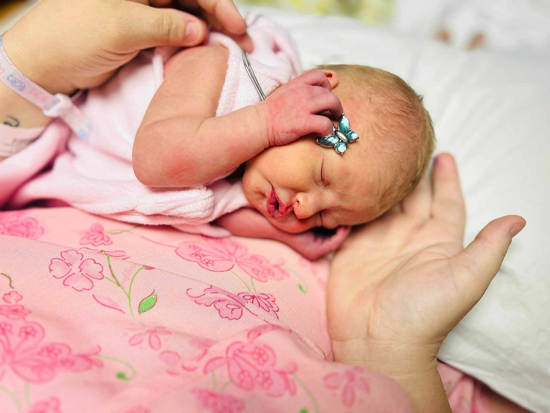 Kaylynn is registered to the contest to win money with this photo: newborn, baby, infant, sleeping, hand, pink, butterfly_clip, closeup, skin, soft, fabric, floral_pattern, peaceful, cute, resting, tiny, adult_hand, bed, blanket, portrait