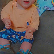 Jay joined the competition — help win amazing prizes! baby, child, smiling, sitting, indoor, shorts, shirt, footwear, couch, blanket, blue, peach, cute, face, portrait, happy, infant, person, young, clothing