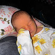 Everleigh is registered to the contest to win money with this photo: newborn, baby, sleeping, infant, onesie, floral_pattern, pillow, cozy, closeup, peaceful, cute, child, indoors, portrait, soft_lighting, resting, small, human, face, hand