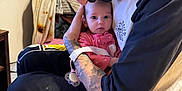 Everleigh is registered to the contest to win money with this photo: baby, man, tattoo, indoor, holding, pajamas, pink, face, head, person, caring, love, family, furniture, blanket, seated, closeup, expression, gentle, bond