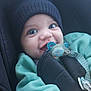 adorable, baby, baby_clothes, blue_eyes, car_seat, child, child_safety, closeup, cute, face, green_clothing, happy, hat, indoor, infant, knit_hat, pacifier, seatbelt, smiling, young_child