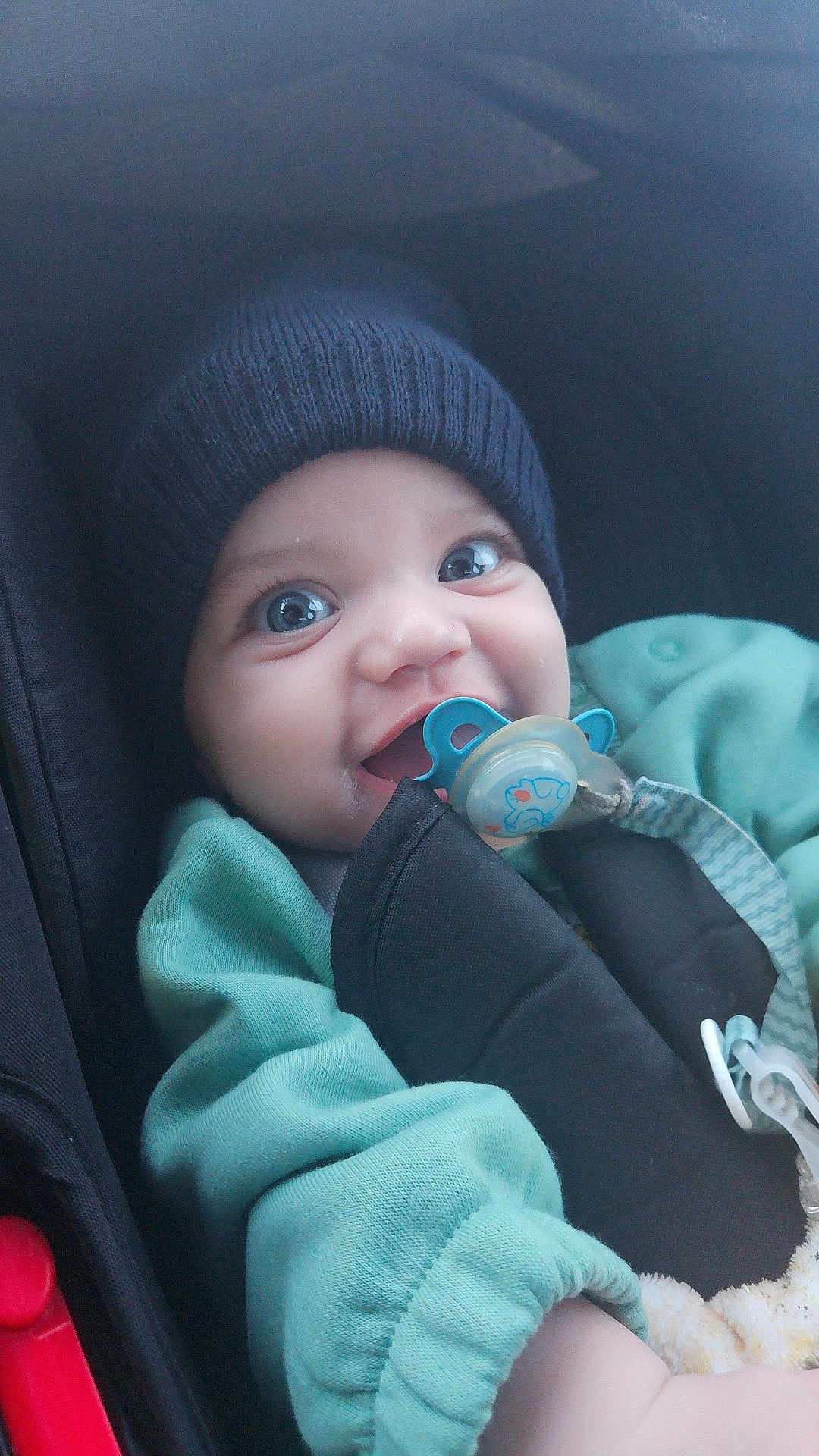 Koceila a rejoint le concours — aidez-le/la à gagner de superbes lots ! adorable, baby, baby_clothes, blue_eyes, car_seat, child, child_safety, closeup, cute, face, green_clothing, happy, hat, indoor, infant, knit_hat, pacifier, seatbelt, smiling, young_child