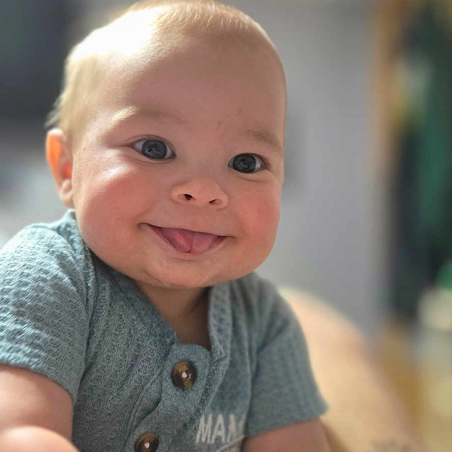 Oliver joined the competition — help win amazing prizes! arm, baby, blue_shirt, blurred_background, buttons, child, close_up, cute, expression, face, hand, happy, indoor, infant, person, portrait, skin, smiling, tongue_out, young