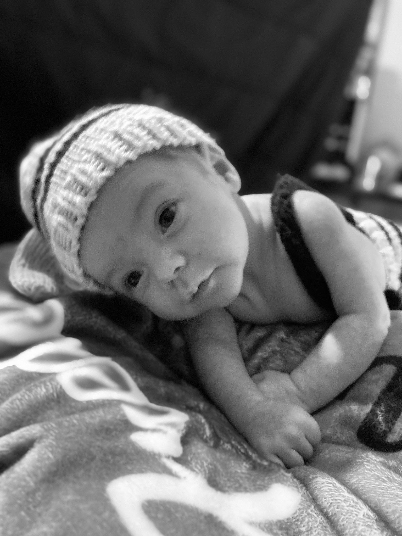 John is registered to the contest to win money with this photo: baby, baby_toddler_clothing, black_and_white, cap, cheek, child, comfort, eye, flash_photography, flooring, fun, grass, happy, headwear, iris, monochrome, monochrome_photography, person, sitting, skin