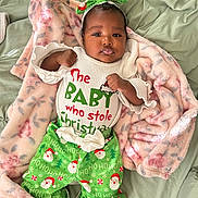 Harmony is registered to the contest to win money with this photo: baby, infant, christmas_clothing, green_pants, headband, bow, blanket, pacifier, lying_down, cute, holiday, festive, smiling, soft_texture, indoors, child, person, white_shirt, colorful, cozy