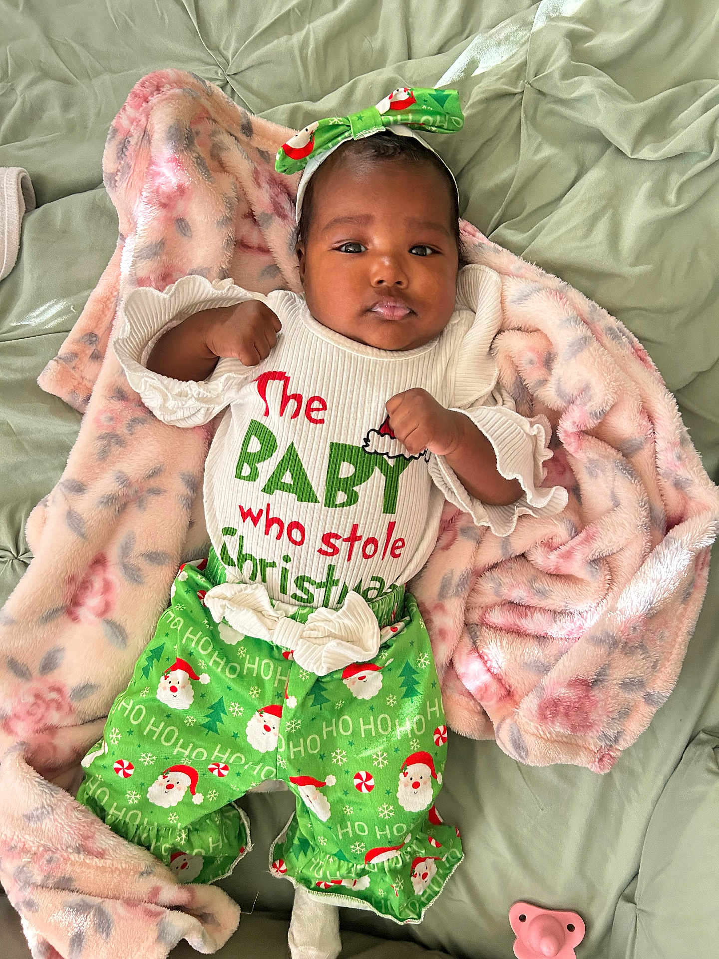 Harmony is registered to the contest to win money with this photo: baby, infant, christmas_clothing, green_pants, headband, bow, blanket, pacifier, lying_down, cute, holiday, festive, smiling, soft_texture, indoors, child, person, white_shirt, colorful, cozy