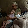 Everlynn is registered to the contest to win money with this photo: baby, infant, elderly_woman, grandmother, sleeping, cuddling, lap, indoor, couch, blanket, portrait, family, caregiving, glasses, gray_hair, pink_clothing, bare_feet, medical_device, living_room, photography
