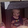 Everlynn is registered to the contest to win money with this photo: baby, child, toddler, playpen, indoor, sitting, side_profile, face, clothing, shirt, colorful, blanket, floral, bedroom, home, furniture, mesh, portrait, infant, safe