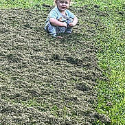 Drake is registered to the contest to win money with this photo: baby, casual_clothing, child, curious, daylight, field, grass, greenery, lawn, mowed_grass, nature, outdoor, park, person, playful, small_child, squatting, summer, toddler, young_child