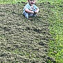 baby, casual_clothing, child, curious, daylight, field, grass, greenery, lawn, mowed_grass, nature, outdoor, park, person, playful, small_child, squatting, summer, toddler, young_child