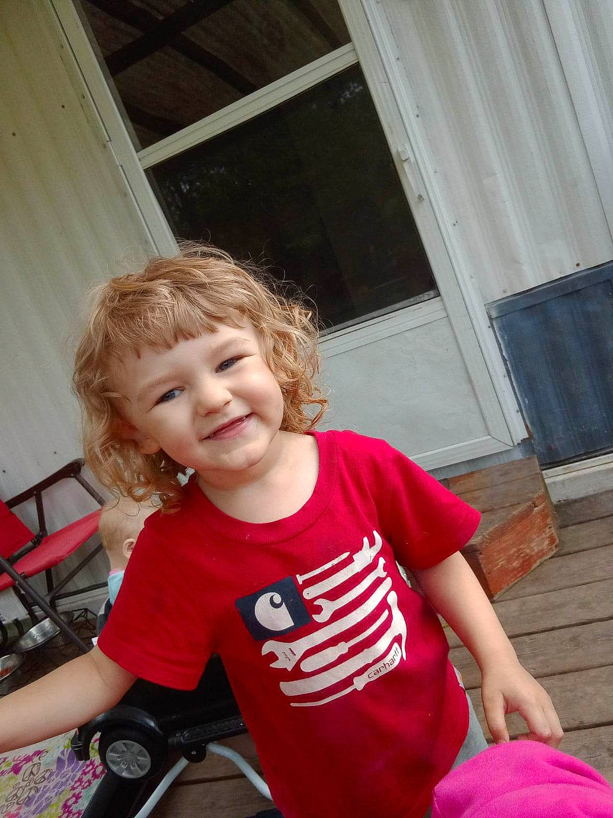 Dylan is registered to the contest to win money with this photo: baby_toddler_clothing, blond, child, eye, face, fun, happy, head, joy, leisure, person, shoulder, sitting, skin, sleeve, smile, standing, t_shirt, toddler, tree