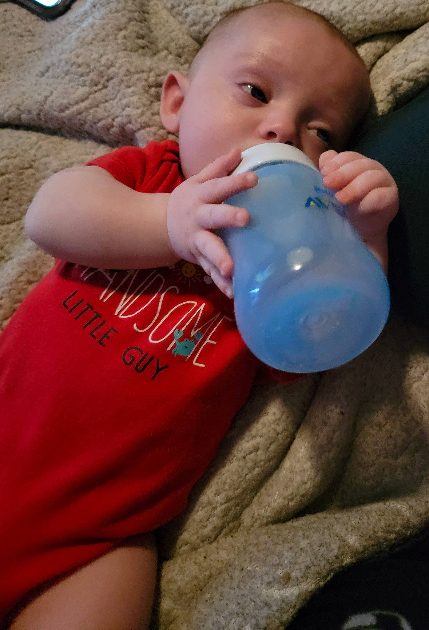 Dominick is registered to the contest to win money with this photo: baby, baby_products, baby_toddler_clothing, chest, child, comfort, drinkware, electric_blue, happy, human_leg, joint, nail, person, plastic, plastic_bottle, sitting, skin, sleeve, t_shirt, thigh
