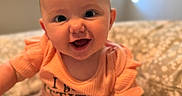 Oakley Wheeler is registered to the contest to win money with this photo: baby, child, infant, smiling, happy, sitting, portrait, indoors, blanket, floral_blanket, orange_clothing, romper, short_sleeves, bald, blue_eyes, open_mouth, window, soft_lighting, cozy, close_up