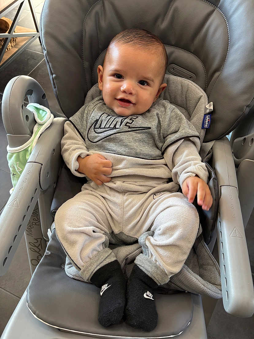 Tony participe au concours pour gagner de l'argent avec cette photo : baby, child, smiling, high_chair, clothing, nike_logo, socks, blanket, indoor, person, cute, comfortable, gray, seat, happy, portrait, infant, young_child, baby_clothes, footwear