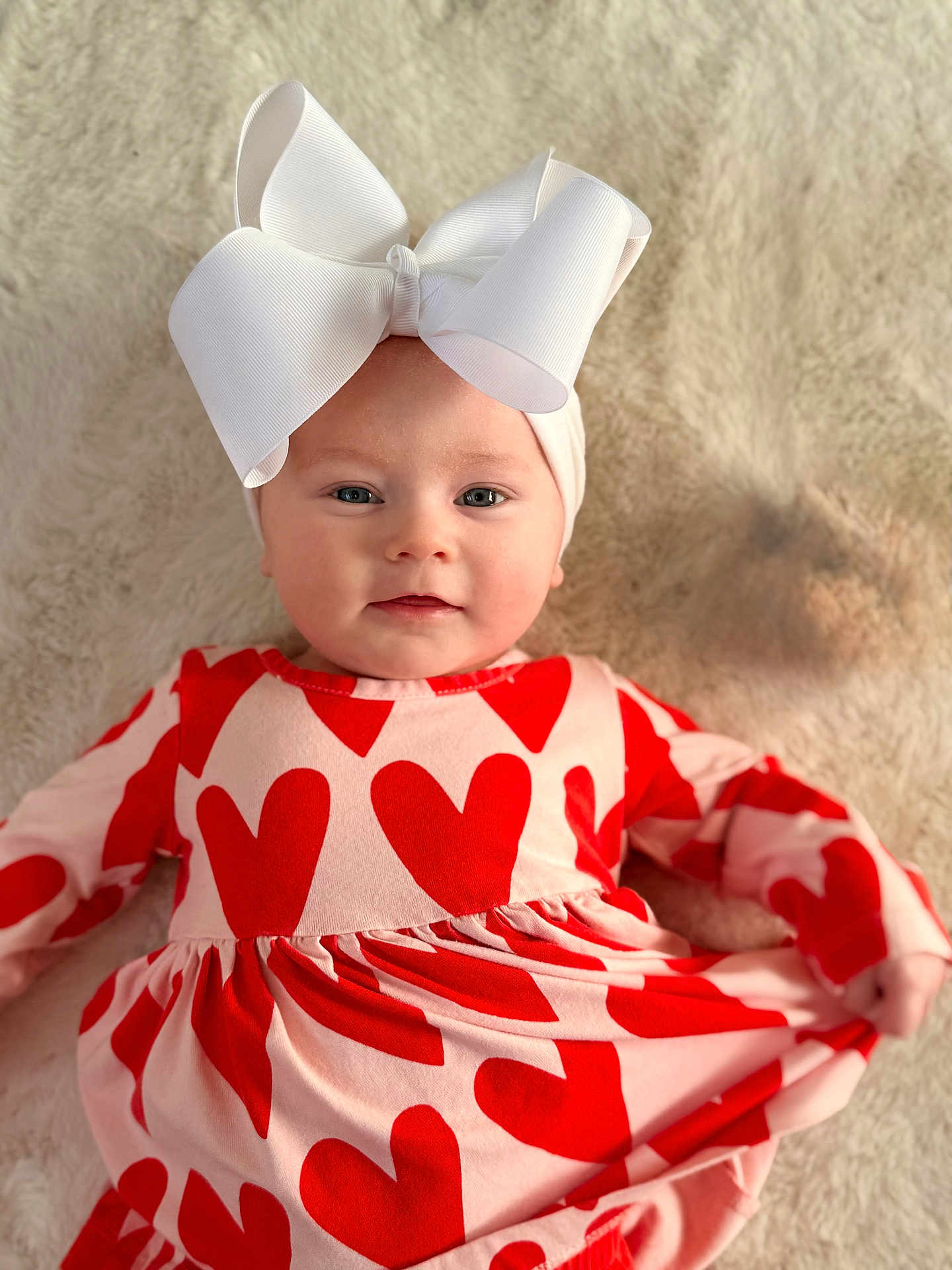 Remi joined the competition — help win amazing prizes! baby, infant, child, headband, bow, dress, hearts, red_and_pink, blanket, portrait, smile, adorable, lying_down, cozy, fabric, clothing, face, eyes, hands, indoor