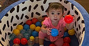 Aurora joined the competition — help win amazing prizes! baby_chair, ball_pit, child, childhood, colorful_balls, curious, cute, floor, home, indoor, living_room, patterned_fabric, pink_clothing, playtime, seated, sofa, soft_toy, toddler, toy, wooden_floor