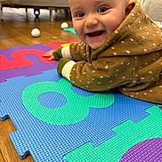 Negan a rejoint le concours — aidez-le/la à gagner de superbes lots ! baby, child, smiling, happy, hooded_sweater, puzzle_mat, colorful, floor, indoor, person, cute, toddler, playtime, blue_eyes, wooden_floor, cozy, clothing, face, expression, home