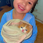 Isabella Bermúdez is registered to the contest to win money with this photo: child, smile, pajamas, kitten, cat, blanket, indoor, wooden_floor, face, person, holding, cute, young, happy, pet, animal, soft, cozy, portrait, warm