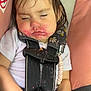 toddler, child, sleeping, car_seat, messy_face, food_stains, hair_bow, white_shirt, black_straps, pink_cushion, gray_cushion, hand, jeans, safety_harness, peaceful, closed_eyes, indoor, cute, young_child, portrait