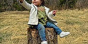 Azarliah Esme is registered to the contest to win money with this photo: toddler, child, tree_stump, flower, grass, forest, pine_trees, jacket, jeans, sneakers, outdoor, nature, sky, smile, holding, sitting, young_child, casual_clothing, daytime, small_plant