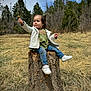 toddler, child, tree_stump, flower, grass, forest, pine_trees, jacket, jeans, sneakers, outdoor, nature, sky, smile, holding, sitting, young_child, casual_clothing, daytime, small_plant