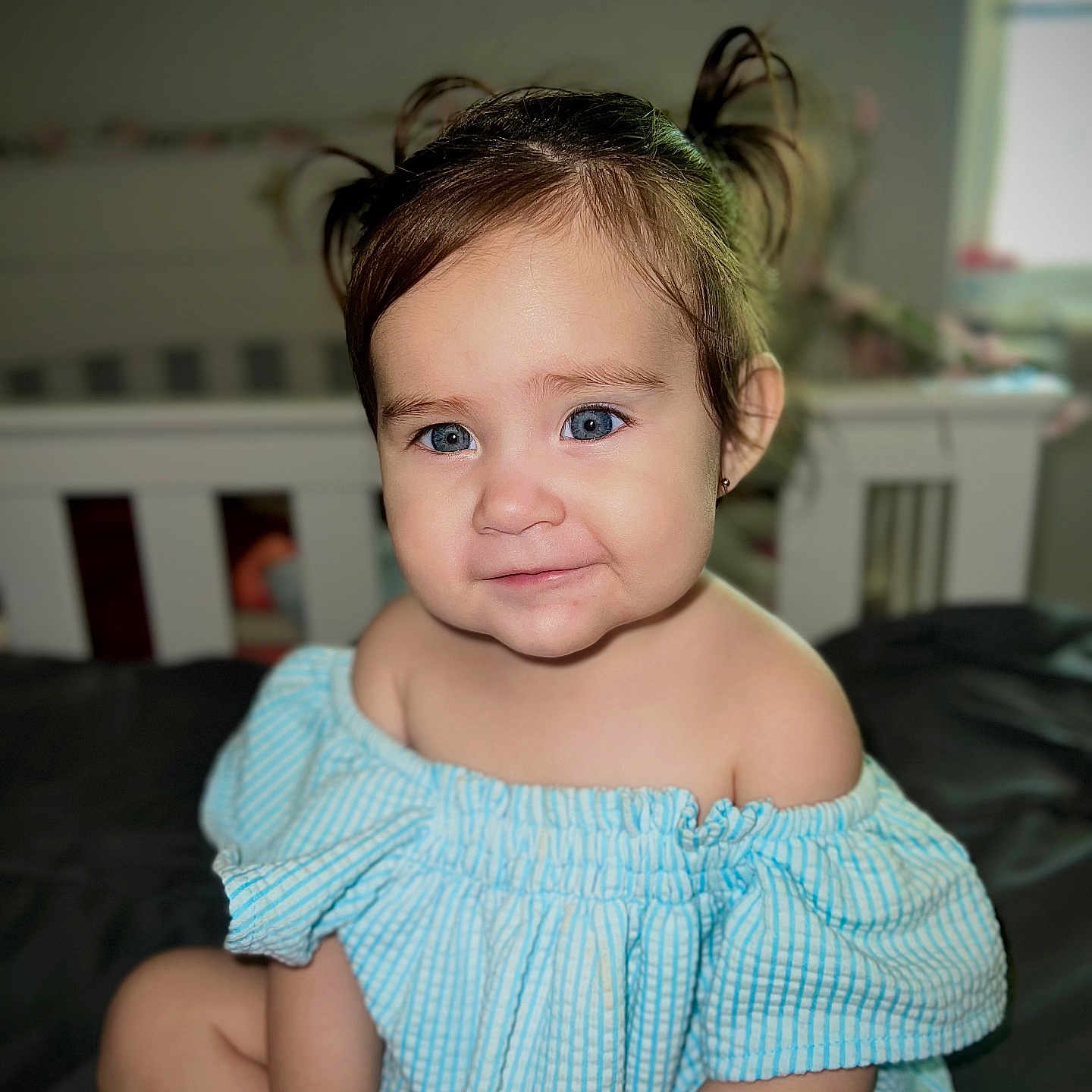 Azarliah Esme is registered to the contest to win money with this photo: baby, bed, blue_eyes, child, cute, furniture, hair, happy, indoor, nursery, off_shoulder_outfit, person, pigtails, portrait, seated, skin, smiling, striped_clothing, toddler, young_child