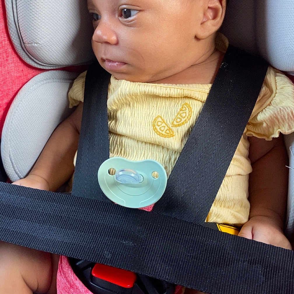 Lariah joined the competition — help win amazing prizes! baby, car_seat, child, infant, pacifier, yellow_clothing, black_strap, red_padding, gray_padding, safety_belt, cute, side_profile, skin, legs, foot, seat, comfort, portrait, indoors, young_child