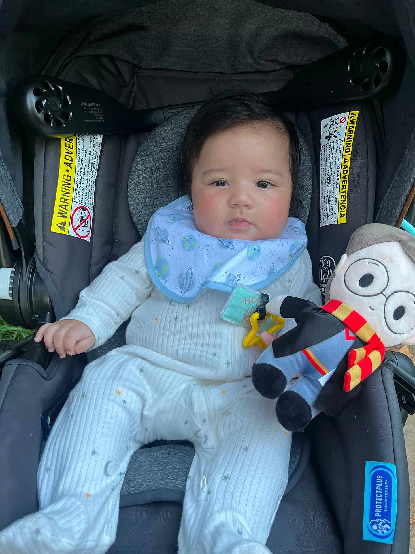 Matthew is registered to the contest to win money with this photo: baby, car_seat, plush_toy, bib, onesie, child, infant, toy, face, clothing, indoor, seat, warning_label, smiling, cute, young_child, comfort, person, portrait, holding