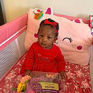 Chloe is registered to the contest to win money with this photo: baby, blanket, bouquet, child, crib, eyes, face, flowers, headband, indoor, patterned_sheet, pink_pillow, plush_pillow, portrait, red_dress, sitting, soft_toys, teething_toy, toddler, toy