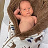 baby, blanket, cozy, infant, wrapped, deer_pattern, relaxed, skin, arm, head, sleeping_area, soft_texture, cute, newborn, lying_down, portrait, expression, indoors, comfort, resting