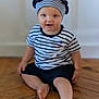 toddler, child, striped_shirt, beret, hat, red_pom_pom, blue_eyes, sitting, wooden_floor, barefoot, indoor, curious, smiling, person, flooring, casual_clothing, young_child, portrait, headwear, cute